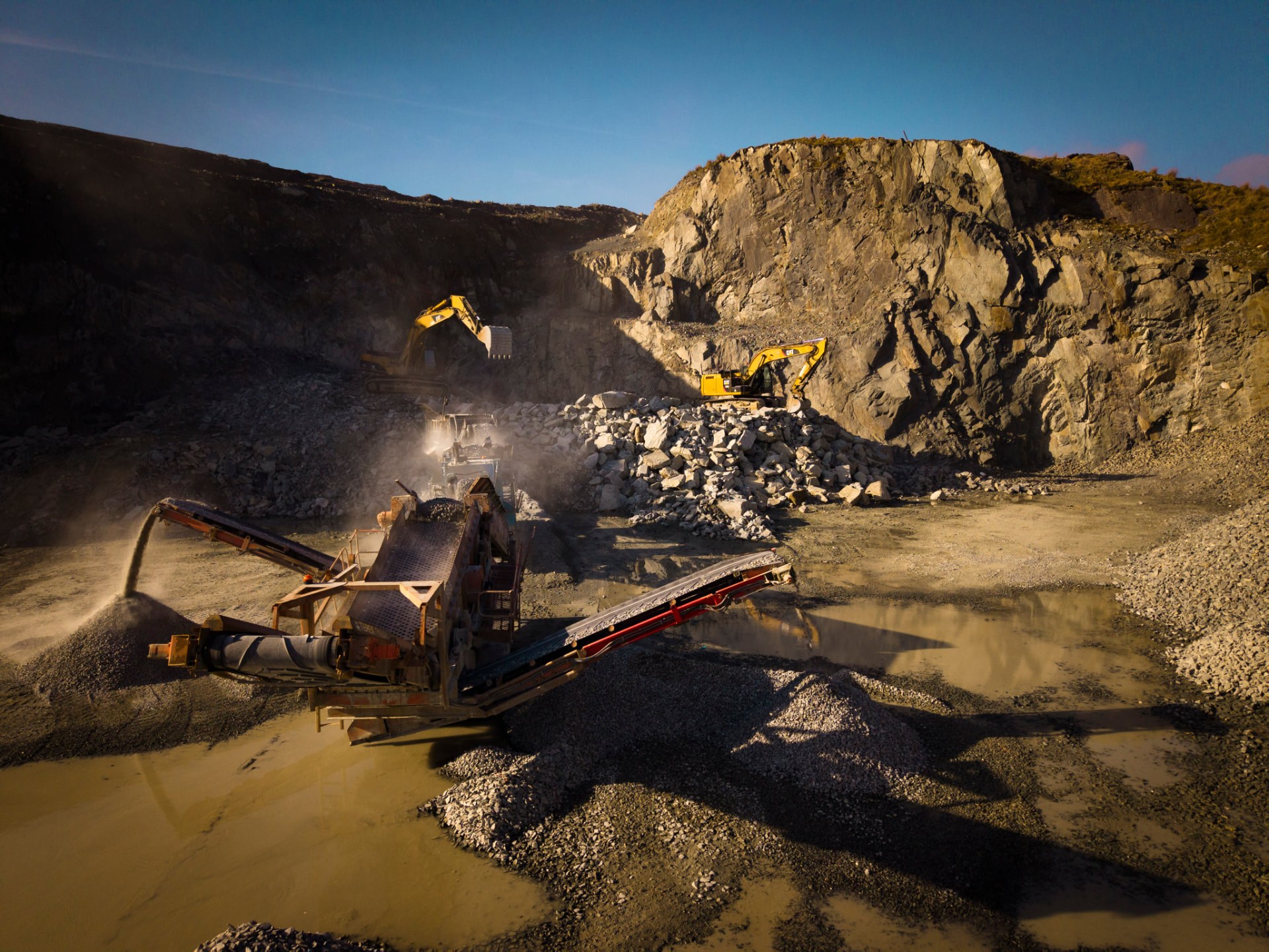 Quarry machinery and excavators working the rock face at golden hour