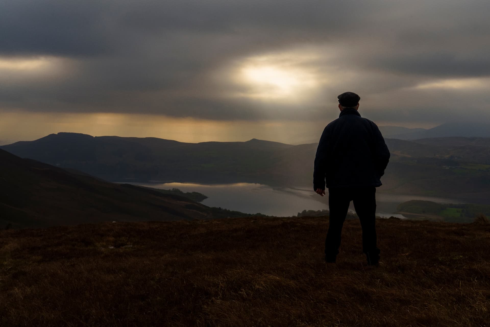 A lone figure on a Kerry hillside looking out over the lake at dusk
